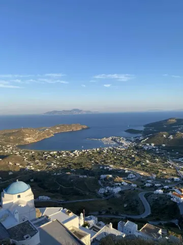 Cycladic bay and whitewashed village seen from above, blue chapel dome in the foreground, Greece