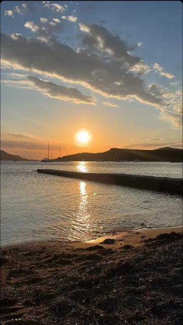 Sunset over a Greek bay, sailing boats at anchor below the hills