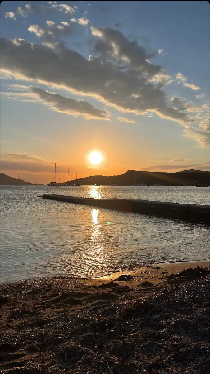 Sunset over a Greek bay, sailing boats at anchor below the hills