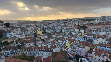 Lisbon rooftops at dusk from a viewpoint, the Tagus on the horizon