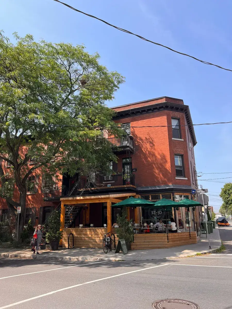 Red-brick building and café terrace with green parasols on the Plateau, Montreal